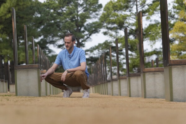 Austin Allen touches a memorial for his deceased father, Ted Allen, in the Field of Empty Chairs section of the Oklahoma City National Memorial & Museum on March 12, 2025. Austin was 4 years old when his father died in the bombing of the Alfred P. Murrah Federal Building. (AP Photo/LM Otero)