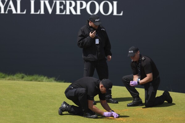 Police clear away debris after protesters threw material onto the 17th green during the second day of the British Open Golf Championships at the Royal Liverpool Golf Club in Hoylake, England, Friday, July 21, 2023. (AP Photo/Peter Morrison)
