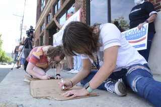Chelsea Balulis, of Pottsville, front, and Ashlee Reick, of Auburn, make signs at a rally hosted by Todd Zimmerman and Schuylkill Democratic Action Group to support the United States Postal Service along Progress Avenue, Thursday, Aug. 20, 2020, in Pottsville, Pa., in front of U.S. Rep. Dan Meuser's, R-Penn., office. Attendees were encouraged to buy a book of forever stamps to support the post office. (Lindsey Shuey/Republican-Herald via AP)