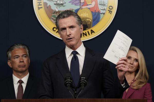 FILE - California Gov. Gavin Newsom displays a bill he just signed that shields abortion providers and volunteers in California from civil judgements from out-of-state courts during a news conference in Sacramento, Calif., Friday, June 24, 2022. Newsom angrily denounced the Supreme Court decision to overturn Roe v. Wade. (AP Photo/Rich Pedroncelli, File)