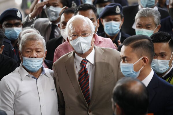 Former Malaysian Prime Minister Najib Razak, center, wearing a face mask with his supporters arrives at courthouse in Kuala Lumpur, Malaysia, Tuesday, July 28, 2020. Najib arrived for a verdict in the first of several corruption trials linked to the multibillion-dollar looting of the 1MDB state investment fund. (AP Photo/Vincent Thian)
