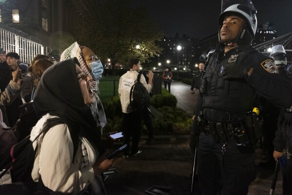 Pro-Palestine student activists face off with New York Police Department officers during a raid on Columbia University's campus at the request of Columbia University President Minouche Shafik on Tuesday evening, April 30, 2024 in New York. NYPD officers, including those from the police department's Strategic Response Group, arrested approximately 100 people as they dismantled encampments and removed individuals occupying Hamilton Hall. (Seyma Bayram via AP)