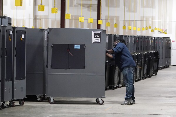 A worker returns voting machines to storage at the Fulton County Election preparation Center Nov. 4, 2020, in Atlanta. (AP Photo/John Bazemore)