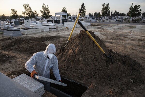 Member of Hevra Kadisha, an organization which prepares bodies of deceased Jews for burial according to Jewish tradition, prepares the grave before a funeral of a Jewish man who died from coronavirus in the costal city of Ashkelon, Israel, Thursday, April 2, 2020. (AP Photo/Tsafrir Abayov)