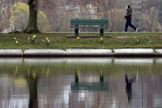 A woman wearing a protective mask walks along the Esplanade, Friday, May 1, 2020, in Boston. (AP Photo/Michael Dwyer)