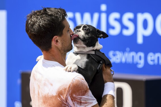 The winner Pedro Cachin of Argentina kisses his dog Tango after the victory against Albert Ramos-Vinolas of Spain during their final match at the Swiss Open tennis tournament in Gstaad, Switzerland, Sunday, July 23, 2023. (Jean-Christophe Bott/Keystone via AP)