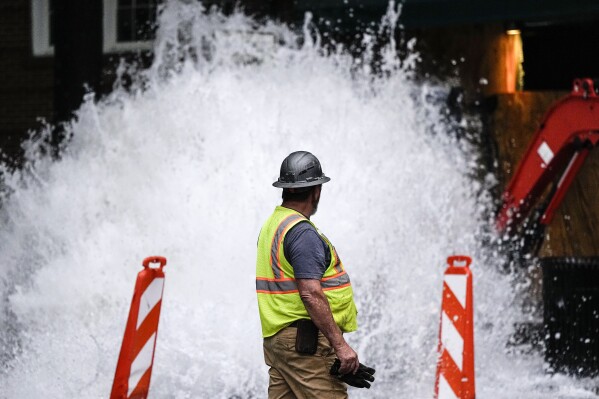 A crew member walks near a broken water transmission line, Saturday, June 1, 2024, in Atlanta. Much of Atlanta, including all of downtown, has been without water since Friday afternoon after crews began work to repair breaks on transmission lines in the downtown area. (AP Photo/Mike Stewart)