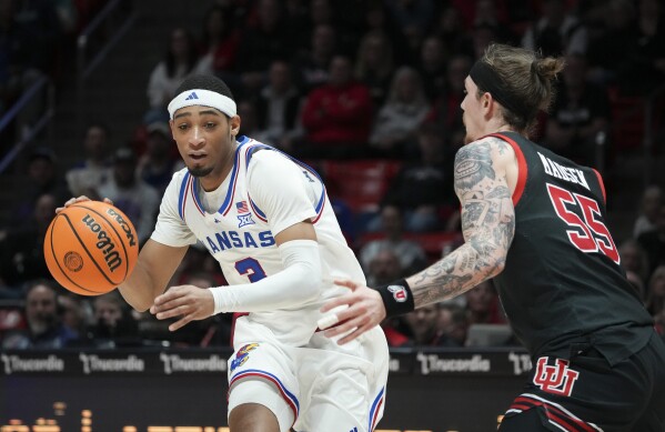 Kansas guard Dajuan Harris Jr. dribbles around Utah guard Gabe Madsen (55) during the first half of an NCAA college basketball game Saturday, Feb. 15, 2025, in Salt Lake City. (AP Photo/Bethany Baker)