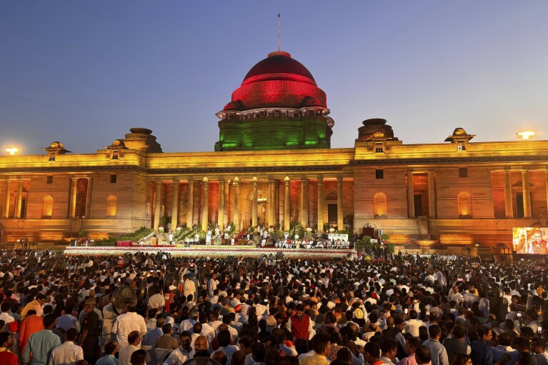 Orang-orang menyaksikan Narendra Modi mengambil sumpah sebagai Perdana Menteri India di hadapan Presiden Draupadi Murmu di Rashtrapati Bhawan, di New Delhi, India, Minggu, 9 Juni 2024. Pemimpin berusia 73 tahun itu hanyalah Perdana Menteri India kedua yang mempertahankan kekuasaan untuk istilah ketiga.  (Foto AP/Manish Swarup)