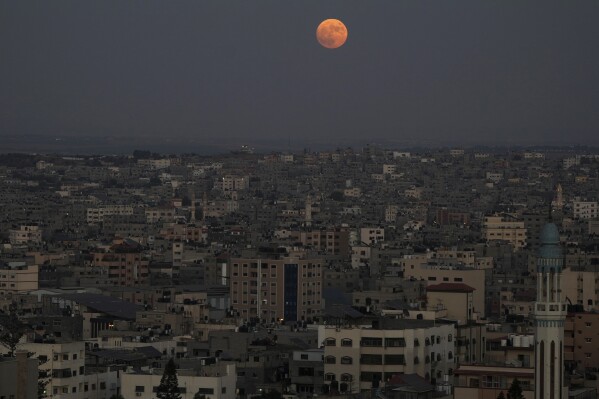 The supermoon rises in the sky over the houses of Gaza City, Wednesday, Aug. 30, 2023. (AP Photo/Adel Hana)