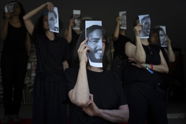 Relatives and supporters of Israeli hostages held by Hamas in Gaza hold photos of their loved ones during a performance calling for their return in Tel Aviv, Israel, Thursday, May 23, 2024. (AP Photo/Oded Balilty)