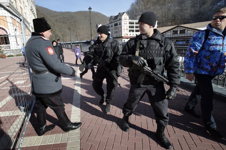 FILE - Russian security forces shake hands with a Cossack as they patrol the streets of the Rosa Khutor ski resort in Krasnaya Polyana, Russia, ahead of the Sochi 2014 Winter Olympics, Friday, Feb. 7, 2014. Fears of possible attacks loomed over the Sochi Games but didn't materialize amid sweeping security measures. (AP Photo/Christophe Ena, File)
