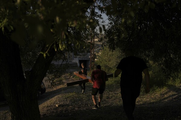 Members of the Maronite Church of St. George carry a wooden cross through an olive grove as they prepare for the traditional Good Friday procession in Quraye, near the southern port city of Sidon, Lebanon, Thursday, April 17, 2025. (AP Photo/Hassan Ammar)