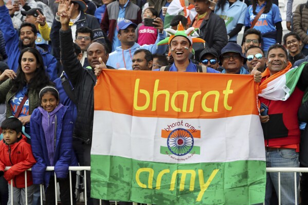 FILE- Indian cricket fans wait for the start of the Cricket World Cup match between India and New Zealand at Trent Bridge in Nottingham, Thursday, June 13, 2019. India has two official names: India, a nomenclature used and accepted in English communication worldwide, and a Sanskrit and Hindi appellation that is “Bharat.” This choice of name is now under spotlight, with Prime Minister Narendra Modi’s government making calls that Indians should rather call their country Bharat and not India. (AP Photo/Rui Vieira, File)