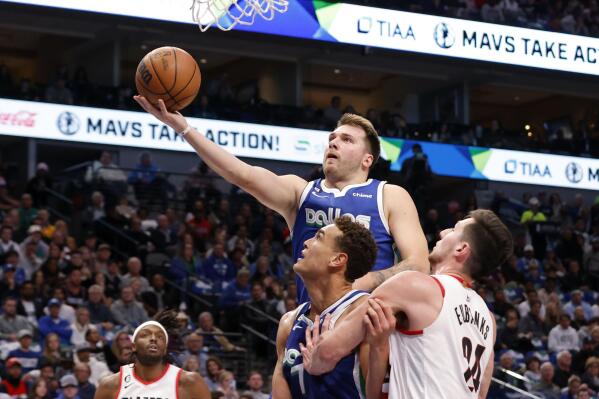 Dallas Mavericks guard Luka Doncic makes a layup next to center Dwight Powell and Portland Trail Blazers forward Drew Eubanks, right, during the first half of an NBA basketball game in Dallas, Saturday, Nov. 12, 2022. (AP Photo/Michael Ainsworth)