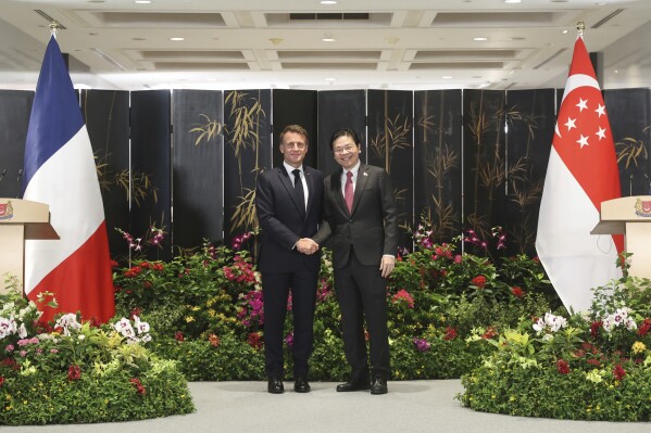 In this photo released by Singapore's Ministry of Digital Development and Information (MDDI), French President Emmanuel Macron, left, shakes hand with Singapore's Prime Minister Lawrence Wong during a joint press conference after ministers from both countries signed multiple bilateral agreements in Singapore, Friday, May 30, 2025.(MDDI via AP)