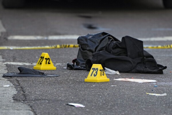 FILE - A witch hat, left, and an unidentified object are shown in the street near evidence markers in the Ybor City section of Tampa, Fla., after a shooting, Oct. 29, 2023. Shootings across the U.S. over the party weekend before Halloween have left at least 11 people dead and more than 70 injured. Authorities say the deaths between Friday and Sunday included two in Tampa, Florida, three in Texarkana, Texas, and two each in Kansas, San Antonio, Texas and Mansfield, Ohio. Many involved altercations arising from Halloween celebrations, including the mass shooting in Tampa’s Ybor City section early Sunday as bars were closing and scores of people in costumes spilled out on the streets. (AP Photo/Chris O'Meara, file)