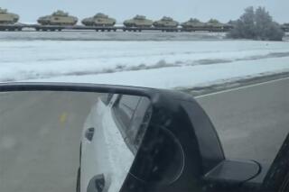 This image from video provided by Eddie Johnson shows a line of tanks and other military combat vehicles traveling by rail along a snowy field along Highway 40 outside of Gorham, Kansas. On Friday, Jan. 27, 2023, The Associated Press reported on stories circulating online incorrectly claiming the video showed a train transporting American tanks and infantry fighting vehicles in Poland, after President Joe Biden announced the U.S. would send tanks to Ukraine.  (Eddie Johnson via AP)