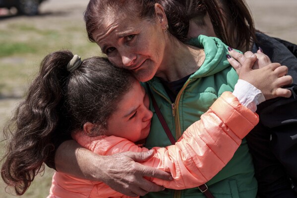 Khrystyna Pyimak, 11, hugs her mother Oksana Velychko, 42, after evacuation from Vovchansk, Ukraine, Sunday, May 12, 2024. Her husband was killed in their house after a Russian airstrike on the city. (AP Photo/Evgeniy Maloletka)