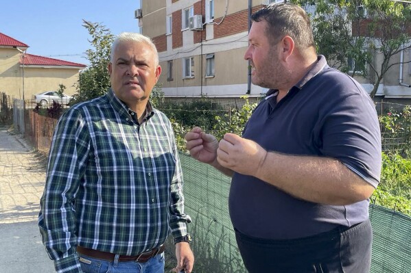 In this image released by the Romanian Defense Ministry, Defense Minister Angel Tilvar, left, speaks to a local resident in a Danube Delta village close to the Ukrainian border, Wednesday, Sept. 6, 2023. Romania's defense minister said Wednesday that pieces apparently of a drone from Russia's recent attacks on Ukraine's port on the Danube River have been found on the territory of his country. Romania is a NATO member. (Romanian Defense Ministry via AP)