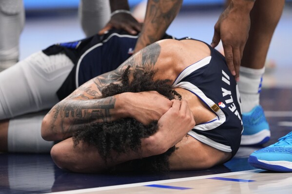 Dallas Mavericks center Dereck Lively II (2) is checked on by teammates after a head injury during the first half in Game 3 of the NBA basketball Western Conference finals against the Minnesota Timberwolves, Sunday, May 26, 2024, in Dallas. (AP Photo/Julio Cortez)