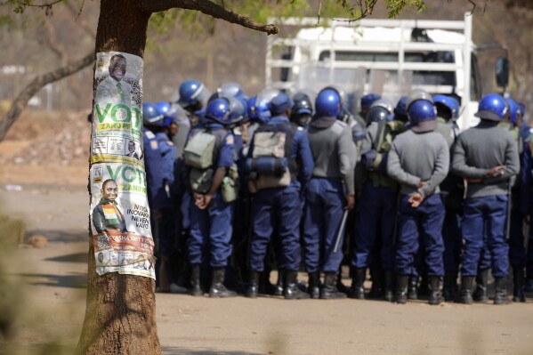 Armed riot police prepare to be deployed on the streets of Harare, Zimbabwe, Friday, Aug. 25, 2023. Hordes of police officers armed with batons, teargas canisters and some with guns were seen next to the result centre as Zimbabweans anxiously waited for the outcome of general elections after polls closed on Thursday and authorities tightened security around the results centre. (AP Photo/Tsvangirayi Mukwazhi)