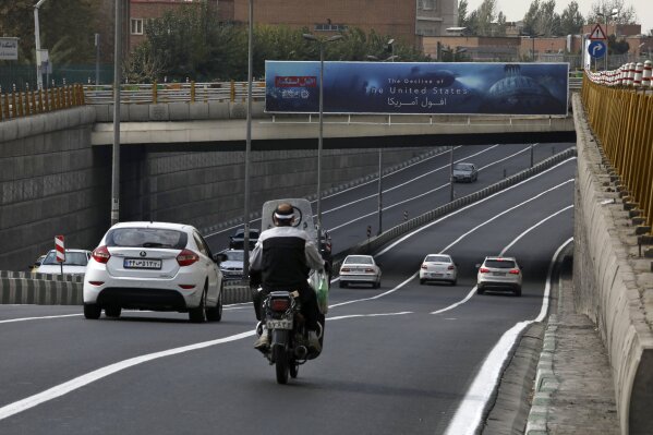 Vehicles pass under an anti-U.S. billboard on a highway in Tehran, Iran, Tuesday, Nov. 3, 2020. The coronavirus pandemic forced authorities to cancel a planned commemoration of the Nov. 4, 1979 takeover of the U.S. Embassy in Tehran. (AP Photo/Vahid Salemi)