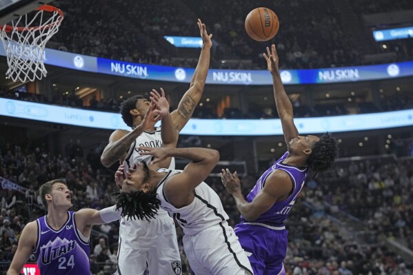 Brooklyn Nets' Nic Claxton, top left, and Cam Thomas, center, defends against Utah Jazz guard Collin Sexton, right, during the first half of an NBA basketball game Monday, Dec. 18, 2023, in Salt Lake City. (AP Photo/Rick Bowmer)