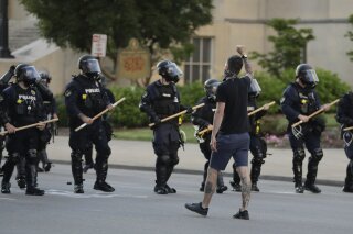 A protester walks with police officers during a protest over the deaths of George Floyd and Breonna Taylor, Saturday, May 30, 2020, in Louisville, Ky. Breonna Taylor, a black woman, was fatally shot by police in her home in March. (AP Photo/Darron Cummings)