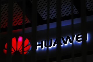 FILE - In this March 8, 2019, file photo, A logo of Huawei retail shop is seen through a handrail inside a commercial office building in Beijing.  The U.S. government is imposing new restrictions on Chinese tech giant Huawei by limiting its ability to use American technology to build its semiconductors. The Commerce Department said Friday, May 15, 2020 the move aims to cut off Huawei’s undermining of existing U.S. sanctions.  (AP Photo/Andy Wong, File)
