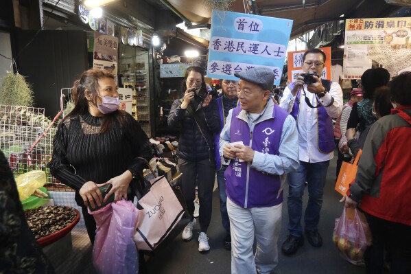 Chui Pak-tai, center, a Taiwanese of Hong Kong descent, greets to Taiwanese voters at a traditional market in New Taipei City, Taiwan, on Dec. 8, 2023. At 72, Chui, a former Hong Kong pro-democracy district councilor who secured Taiwan residency 11 years ago, is running for legislative office. Although he faces long odds, his campaign draws attention to the immigration challenges of the Hong Kong diaspora.(AP Photo/Chiang Ying-ying)