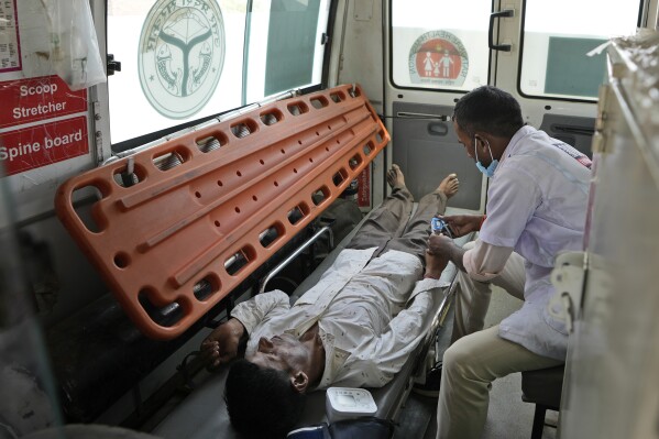 Jitendra Kumar, a paramedic checks the oxygen level of his patient who is suffering from a heat stroke after carrying him in an ambulance from his home in village Mirchwara, 24 kilometers (14.91 miles) from Banpur in Indian state of Uttar Pradesh, Saturday, June 17, 2023. Ambulance drivers and other healthcare workers in rural India are the first line of care for those affected by extreme heat. (AP Photo/Rajesh Kumar Singh)