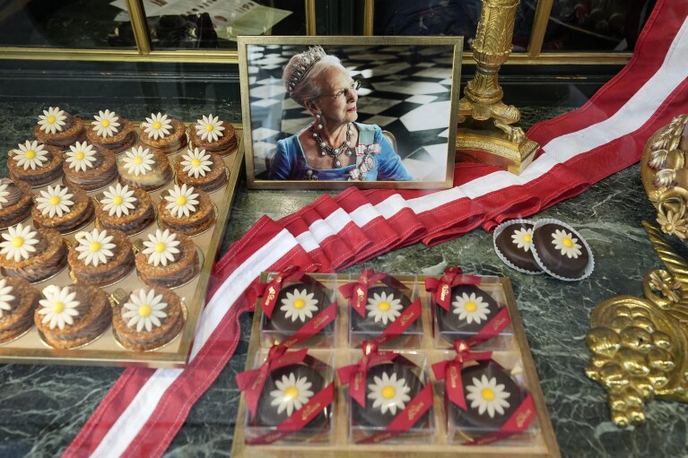 A portrait of Danish Queen Margrethe appears in the window of a candy shop in Copenhagen, Denmark, Sunday, Jan. 14, 2024. Crown Prince Frederik of Denmark takes the crown on Sunday from his mother, Queen Margrethe II, who broke with centuries of Danish royal tradition and retired after a 52-year reign.  (AP Photo/Martin Meissner)