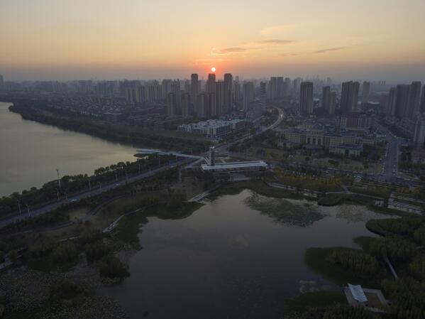 The sun sets near the "Fish Tail" sponge park that's built on a former coal ash dump site in Nanchang in north-central China's Jiangxi province on Sunday, Oct. 30, 2022. The concept of the park involves creating and expanding parks and ponds within urban areas to prevent flooding and absorb water for times of drought. (AP Photo/Ng Han Guan)