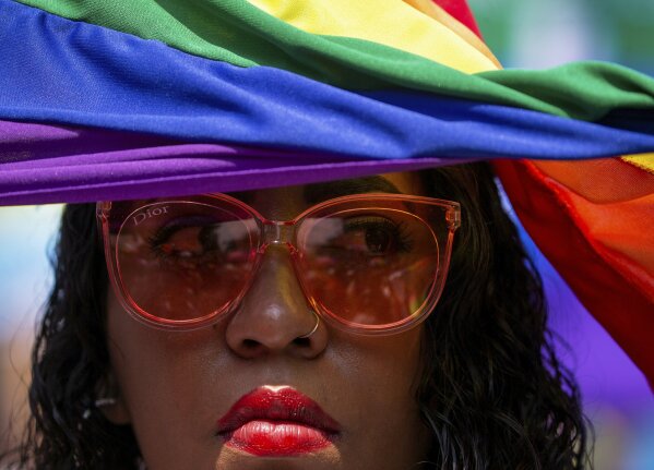 A reveler covers himself from the sun with a rainbow flag during the gay pride parade in Mexico City, Mexico, Saturday, June 29, 2019. (AP Photo/Fernando Llano)