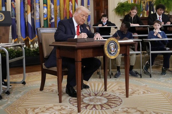 President Donald Trump signs an executive order in the East Room of the White House in Washington, Thursday, March 20, 2025. (AP Photo/Ben Curtis)