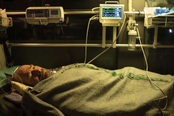Oleksandr, an injured Ukrainian serviceman, lies on a bed inside a medical bus of volunteer battalion 