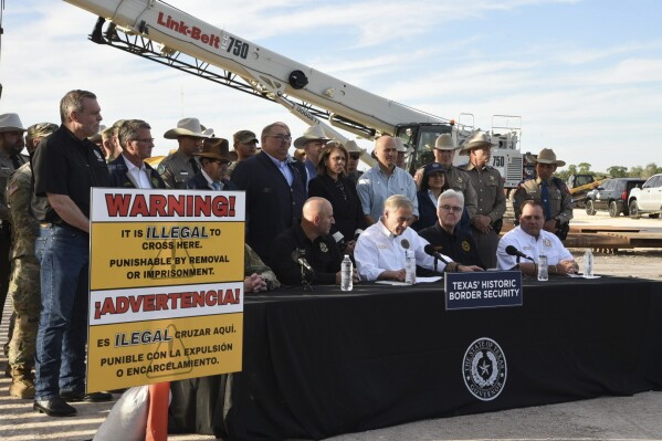 Gov. Greg Abbott signs three bills into law at a border wall construction site in Brownsville, Texas on Monday, Dec. 18, 2023, that will broaden his border security plans and add funding for more infrastructure to deter illegal immigration. (AP Photo/Valerie Gonzalez)