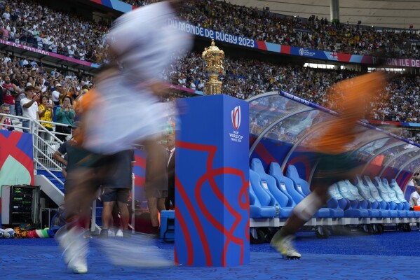 Players run past the World Cup trophy prior to the Rugby World Cup Pool C match between Australia and Georgia at the Stade de France in Saint-Denis, north of Paris, Saturday, Sept. 9 31, 2023. (AP Photo/Thibault Camus)