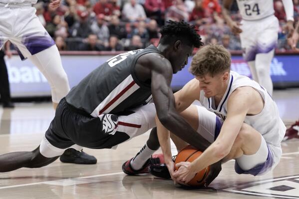 Washington State forward Mouhamed Gueye, left, and Washington guard Cole Bajema scramble for the ball during the first half of an NCAA college basketball game Saturday, Feb. 11, 2023, in Pullman, Wash. (AP Photo/Dean Hare)