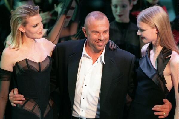 FILE - French fashion designer Thierry Mugler on the catwalk with unidentified models after the presentation of his 1998-99 fall-winter ready-to-wear collection presented in Paris on March 15, 1998. French fashion designer Thierry Mugler, whose dramatic designs were worn by celebrities like Madonna, Lady Gaga and Cardi B, has died. He was 73. A post all in black on his official Instagram account said he died Sunday, Jan. 23, 2022 and “May his soul Rest In Peace." It did not give a cause of death. (AP Photo/Remy de la Mauviniere, File)