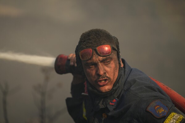 FILE - A firefighter sprays water at a fire on the mount of Penteli, in northern Athens, Greece on July 19, 2022. Greek authorities presented a new action plan on Thursday, March 21, 2024 for tackling wildfires which often ravage the country during its hot, dry summers.(AP Photo/Thanassis Stavrakis, File)