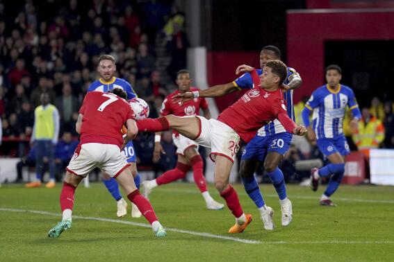 Nottingham Forest's Brennan Johnson, right, makes contact with teammate Neco Williams during the English Premier League soccer match between Nottingham Forest and Brighton & Hove Albion at the City Ground, Nottingham, England, Wednesday, April 26, 2023. (Tim Goode/PA via AP)