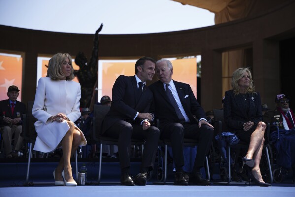 文件——2024年6月6日，星期四，在诺曼底科勒维尔-苏尔-梅尔美国公墓举行的纪念诺曼底登陆日80周年的纪念仪式上，总统乔·拜登和第一夫人吉尔·拜登（右）与法国总统艾曼纽尔·马克隆（左二）和妻子布里吉特·马克隆（Brigitte Macron）坐在舞台上。6月7日，星期五，美联社报道了网上流传的错误消息，称拜登试图坐在法国诺曼底纪念诺曼底登陆80周年的仪式上没有的椅子上。（美联社照片/丹尼尔·科尔，泳池，档案）