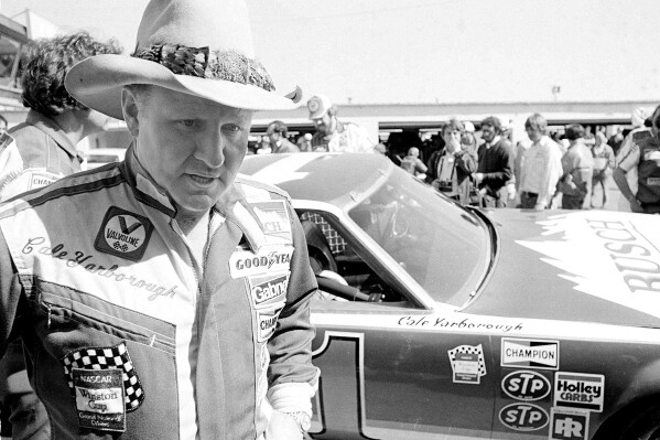 FILE - Cale Yarborough walks away after blowing the engine of his Oldsmobile just after completing his first lap in pole position qualifying for the Daytona 500 in Daytona Beach, Fla., Feb. 11, 1979. Yarborough, considered one of NASCAR's all-time greatest drivers and the first to win three consecutive Cup titles, died Sunday, Dec. 31, 2023. He was 84. (AP Photo/Hal Moore, File)