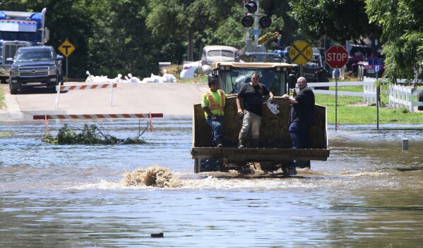 A person holds a dog while being evacuated in the bucket of a front end loader in Hawarden, Iowa, Saturday, June 22, 2024, in the wake of flooding from the Big Sioux River. (Tim Hynds/Sioux City Journal via AP)
