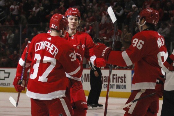 Detroit Red Wings defenseman Moritz Seider (53) celebrates with left wing J.T. Compher (37) and defenseman Jake Walman (96) after scoring against the New Jersey Devils during the second period of an NHL hockey game Wednesday, Nov. 22, 2023, in Detroit. (AP Photo/Duane Burleson)