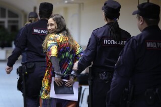 Sasha Skochilenko, a 33 year-old artist and musician, second left, is escorted by officers from the court room for a hearing in the Vasileostrovsky district court in St. Petersburg, Russia, Monday, Nov. 13, 2023. A court in St Petersburg has to deliver a verdict to Skochilenko on charges of spreading "fakes" about the Russian military after she replaced four small price tags in a St. Petersburg supermarket with anti-war slogans. The prosecution asked to sentence her to 8 years in prison. (AP Photo/Dmitri Lovetsky)