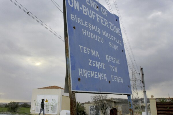 FILE - A woman walks by a UN sign at the UN buffer zone inside Pyla village, outskirt of coastal city of Larnaca, Cyprus, Thursday, Jan. 8, 2009. The head of the U.N. peacekeeping mission in ethnically split Cyprus said Monday, Oct. 9, 2023 that Greek Cypriots and Turkish Cypriots have reached an “understanding” over a contentious road inside a U.N.-controlled buffer zone whose construction had stirred up tensions not seen in years. (AP Photo/Petros Karadjias, File)