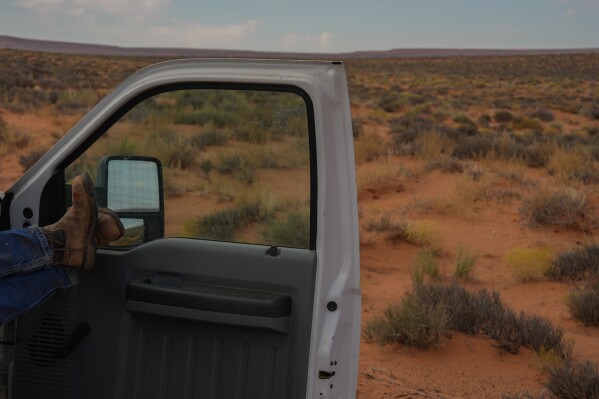 CORRECTS LAST NAME TO ATENE FROM BLACK - Robert Atene, a project leader with the Navajo Tribal Utility Authority, relaxes in a truck during a lunch break while installing power line poles at a home, Tuesday, Oct. 8, 2024, on the Navajo Nation in Halchita, Utah. (AP Photo/Joshua A. Bickel)